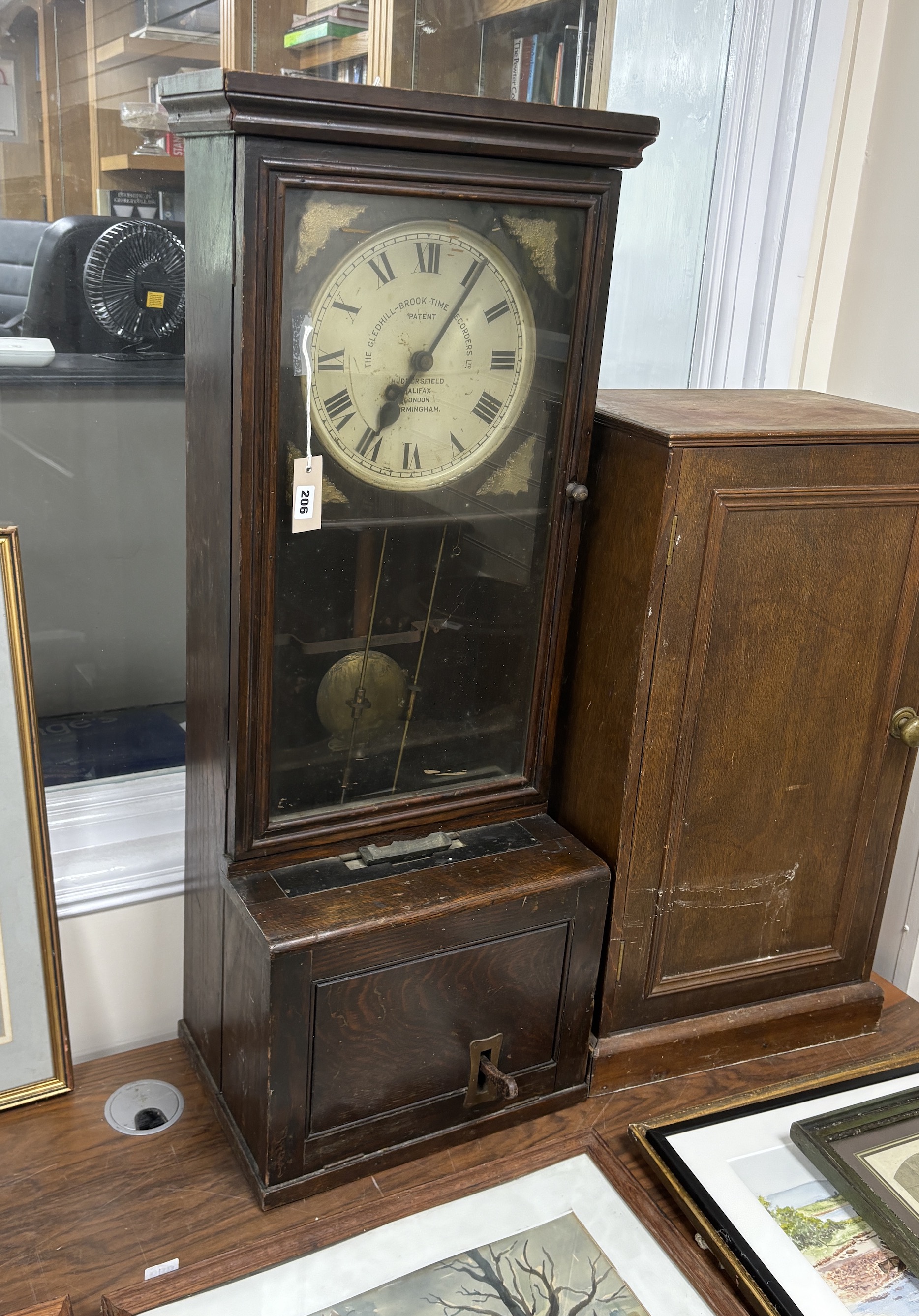 A Gledhill-Brook Time Recorder clocking-in machine, on associated cupboard, combined height 183cm